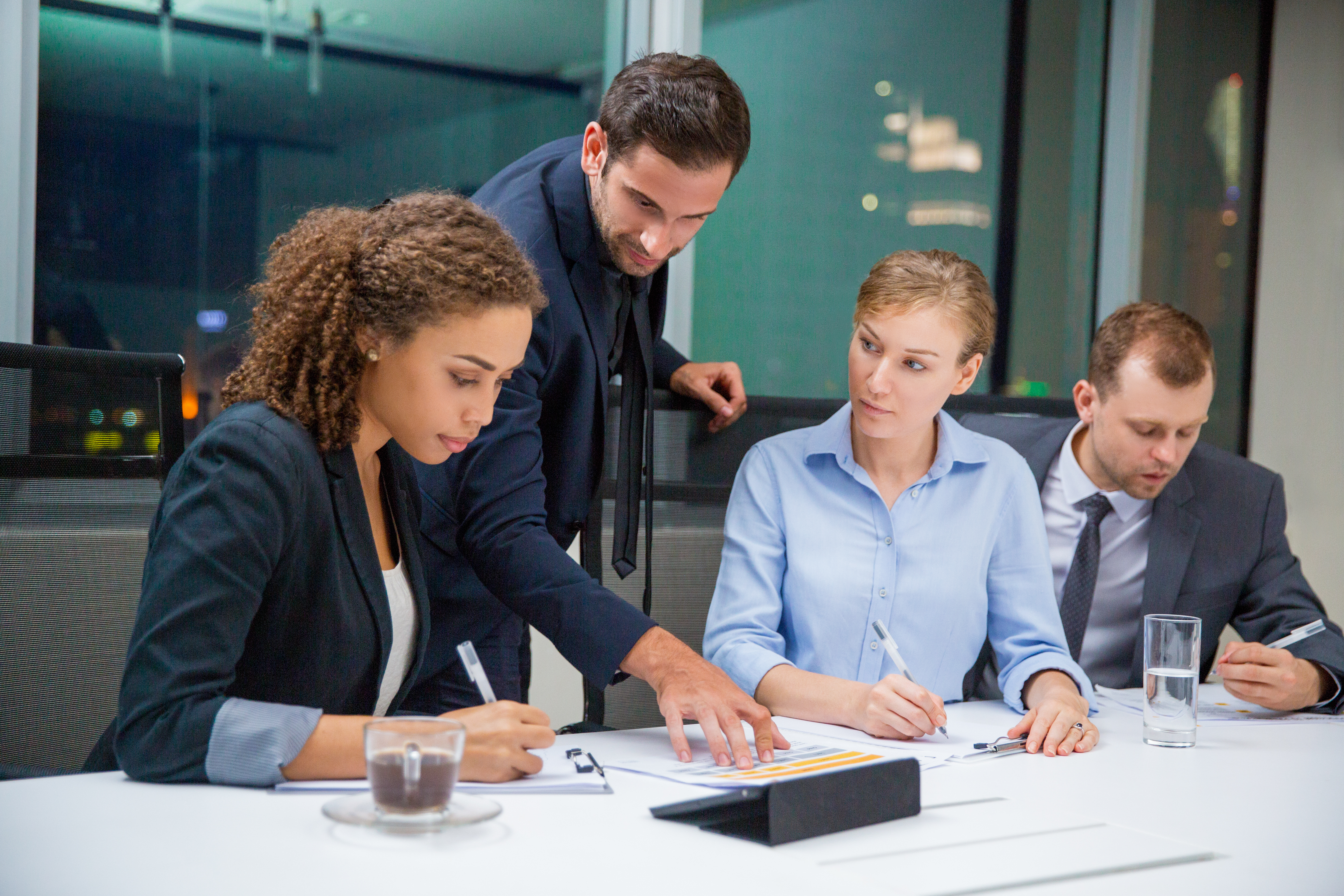 Business People Discussion Business people sitting in conference room and discussing business issues. Executive manager standing, pointing to document and explaining his idea to business team