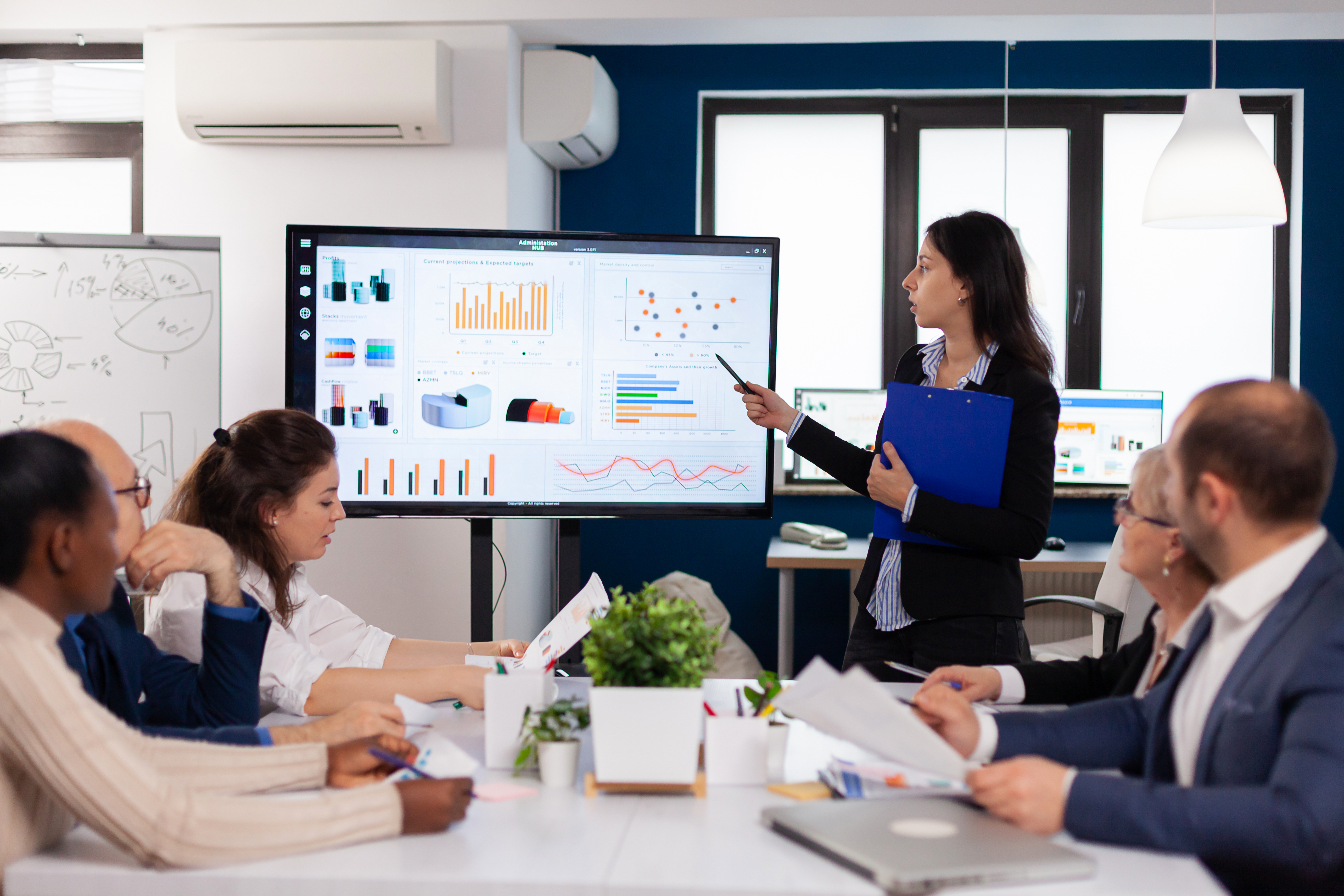 Young team leader in big corporation briefing coworkers Young team leader in big corporation briefing coworkers pointing at graph meeting. Corporate staff discussing new business application with colleagues looking at screen